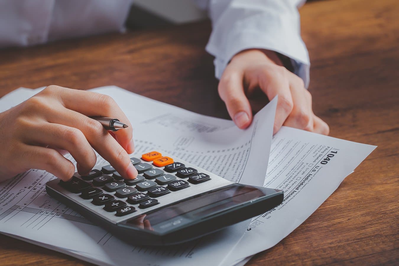 Hands using a calculator over a 1040 tax form